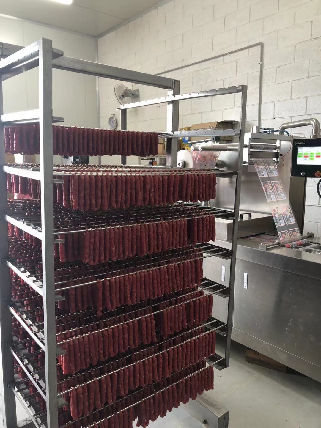 Sausages waiting to be put into the bag; next to it is a vacuum packaging machine in operation